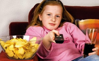 Niña comiendo chatarra frente al televisor